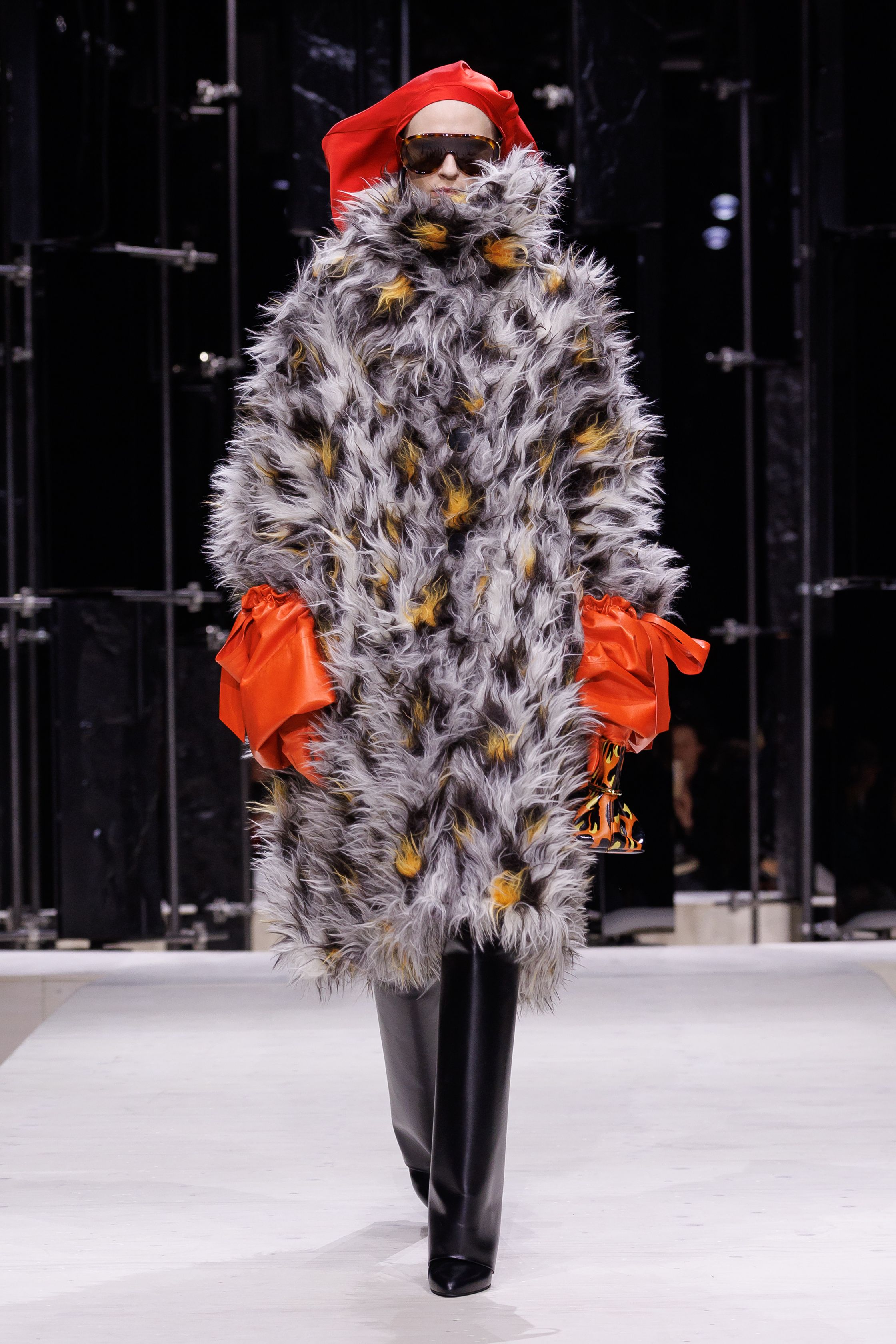 Givenchy 2026秋冬在现代建筑空间中呈现一场充满戏剧性的时装叙事：雕塑式西装、亮色斗篷、结构礼服与夸张装饰共同构建品牌标志性的高级时装气质。蓝色、红色与黄色的高饱和色彩与黑白经典形成鲜明对比，服装通过立体剪裁与夸张廓形展现出强烈视觉张力。整场系列在优雅与戏剧之间取得平衡，展现现代高级时装的力量-顽石频道趋势研究